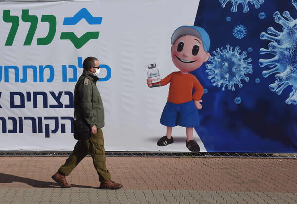 A man walks outside an Israeli vaccination center in Jerusalem, on Tuesday, January 12, 2021. Israel will expand the vaccination drive inoculating teachers and people over 50 years on Wednesday.  JER2021011218 DEBBIExHILL