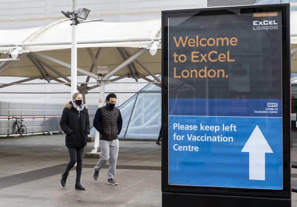 (210113) -- LONDON, Jan. 13, 2021 -- People wearing face masks walk past the Vaccination Centre at ExCel exhibition centre in London, Britain, Jan. 12, 2021. British Prime Minister Boris Johnson on Monday warned against false complacency as the country is seeking to speed up the coronavirus vaccine rollout. According to the prime minister, 2.4 million coronavirus jabs have been administered across Britain. Seven new mass vaccination sites in England opened Monday, as the country races against time to bring the pandemic under control. ) BRITAIN-LONDON-COVID-19-VACCINE ROLLOUT HanxYan 