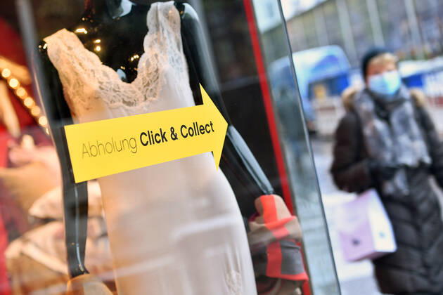 Theme picture Pick up Click and Collect in Munich on 12 01 2021 A directional arrow is stuck to a shop window of a clothing store with the notice to pick up goods ordered online in the store