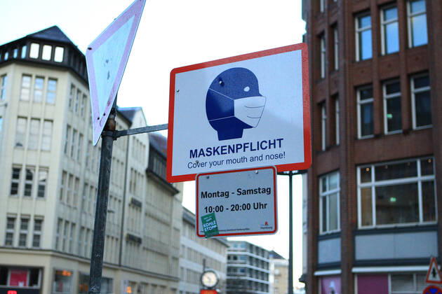 A sign attached to a lamppost indicates that masks are compulsory at certain times in Mönckebergstraße in Hamburg Altstadt Hamburg
