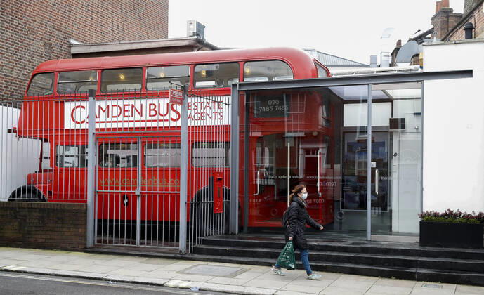 (210120) -- LONDON, Jan. 20, 2021 -- A woman wearing a face mask walks past an Estate Agent in the shape of a red double decker in London, Britain, on Jan. 19, 2021. The number of people who have died within 28 days of a positive coronavirus test has surpassed the grim milestone of 90,000 in Britain after another 1,610 were confirmed, according to official figures released Tuesday. The latest daily death toll, the highest since the pandemic began in the country, brought the total number of coronavirus-related deaths in Britain to 91,470, the data showed. ) BRITAIN-LONDON-COVID-19-DEATH TOLL HanxYan