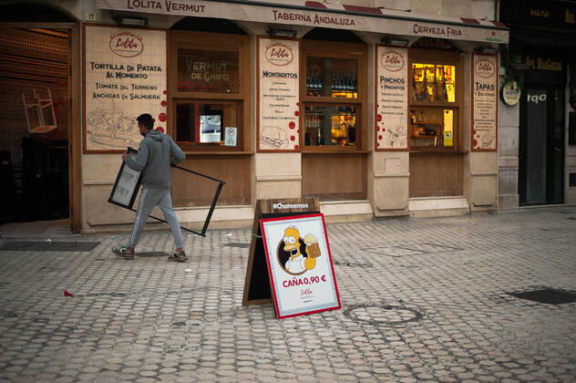 January 22, 2021, Malaga, Spain: A poster with the image of character Homer Simpson offering beers seen outside Lolita Vermut bar as an employee carries a board during the mandatory closure..The third wave of coronavirus disease has impacted most daily income in the Andalusia region after the Christmas holidays. Following the increase of infections, several regional governments decided to take new measures such as limiting mobility perimeters between cities and towns and closing hospitality and commercial sectors in the afternoon. Malaga Spain - ZUMAs197 20210122_zaa_s197_081 Copyright: xJesusxMeridax