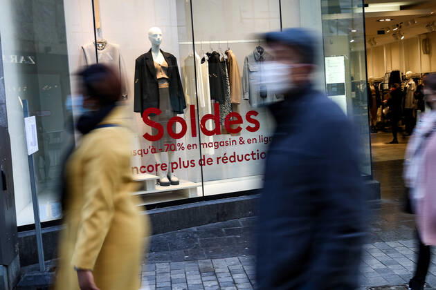 (210123) -- BRUSSELS, Jan. 23, 2021 -- People wearing face masks walk past a shop with sales posters in Brussels, Belgium, Jan. 22, 2021. The annual Belgian winter sales kicked off on Jan. 4. To boost consumption, the scheduled four-week-long winter sales have been extended by two weeks until Feb. 15. ) BELGIUM-BRUSSELS-COVID-19-WINTER SALES ZhangxCheng 