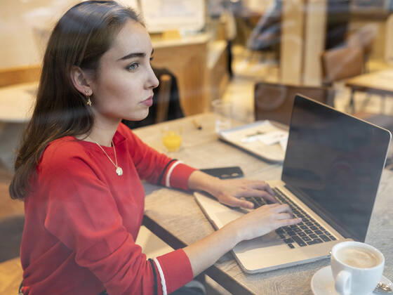 Thoughtful woman with laptop seen through glass of cafe model released Symbolfoto JCCMF00247