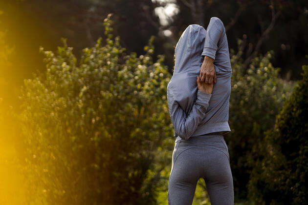 Athlete stretching hands while standing at park model released Symbolfoto MAUF03697
