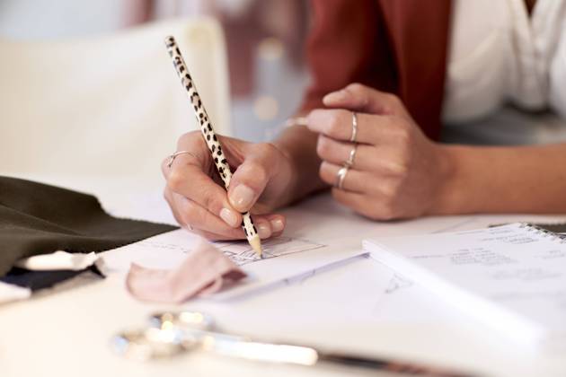Female fashion professional drawing design on paper at desk in atelier model released Symbolfoto property released VEGF03422