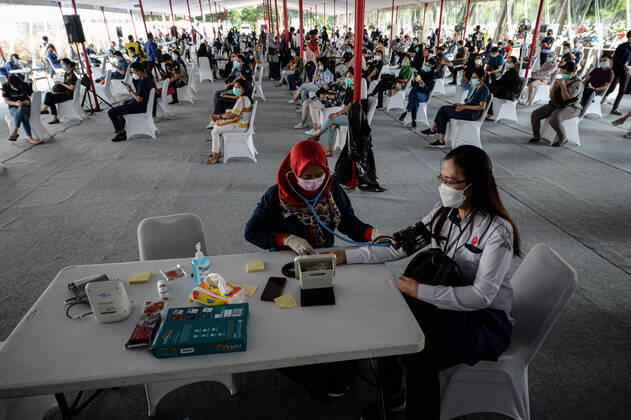 (210204) -- JAKARTA, Feb. 4, 2021 -- A health worker (R, front) has her physical condition checked before receiving a dose of China s Sinovac COVID-19 vaccine during mass vaccination program for health workers as a main priority group in Jakarta, Indonesia, Feb. 4, 2021. ) INDONESIA-JAKARTA-MASS VACCINATION PROGRAM-COVID-19 AgungxKuncahyaxB. 