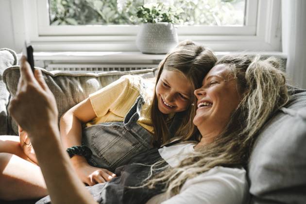 Smiling mother and daughter using digital tablet in living room Sweden, Gothenburg, model released, property released Copyright: xMaskotx , MA83761