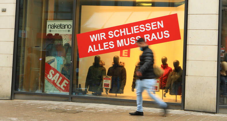 A sticker is stuck in the window of a clothing store closed during the lockdown, indicating that a clearance sale is coming up due to the store closing Downtown Hamburg