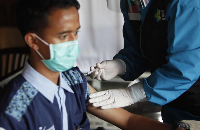 Indonesia s COVID-19 Mass Vaccination A health worker vaccinates her colleague during COVID-19 mass vaccination for medical workers and elderly health workers in Bogor, West Java on February 11, 2021. (Photo by Adrian INA Photo Agency) 