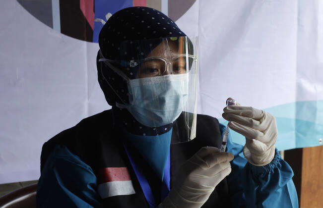 Indonesia s COVID-19 Mass Vaccination A health worker prepares vaccinates her colleague during COVID-19 mass vaccination for medical workers and elderly health workers in Bogor, West Java on February 11, 2021. (Photo by Adrian INA Photo Agency) 