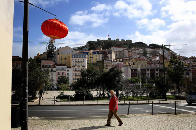 February 12, 2021, Lisbon, Portugal: A men wearing a face mask walks under a red lantern that were put up for the Chinese New Year marking the Year of the Ox at Martin Moniz square in Lisbon, Portugal on February 12, 2021. This year, with restrictions imposed by the state of emergency in Portugal due to the COVID-19 pandemic, online broadcasting replaces Chinese New Year celebrations, such as the traditional parade with dragons, snakes and acrobats, which attracts hundreds of people every year to the Almirante Reis avenue, however the traditional red lanterns adorn the avenue, to mark the event. Lisbon Portugal - ZUMAf123 20210212_zap_f123_004 Copyright: xPedroxFiuzax
