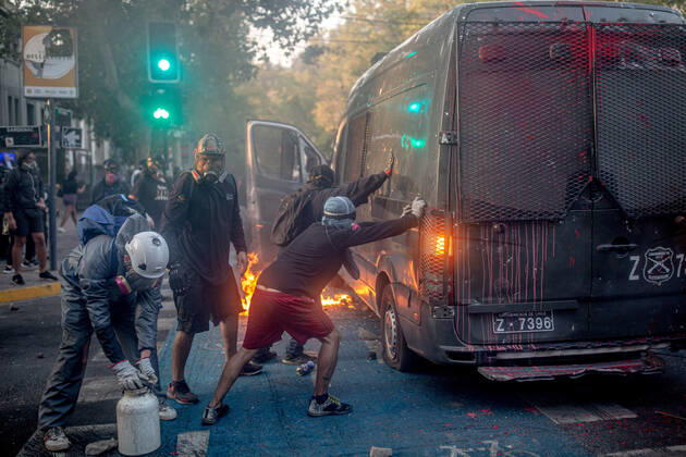 February 12, 2021, Santiago, Region Metropolitana, Chile: Protesters push and try to overturn a burning police vehicle during protests against police brutality in Santiago..Several protesters took to the streets in a protest against President Sebastian Pinera s government, attacking and burning a police vehicle hence injuring an officer following the death of a street artist who was shot by police in the city of Panguipulli after he refused to co-operate with a police search. Santiago Chile - ZUMAs197 20210212_zaa_s197_268 Copyright: xFelipexFigueroax