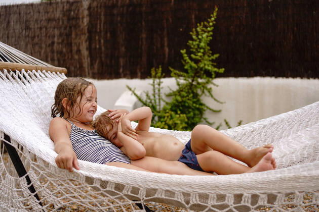 IMAGO Creative, Jahreszeit Sommer, Sommerferien Cute barefooted little sister and brother hugging while lying in hammock and having fun during summer holidays Copyright: xAngelxSantamariax Model Released