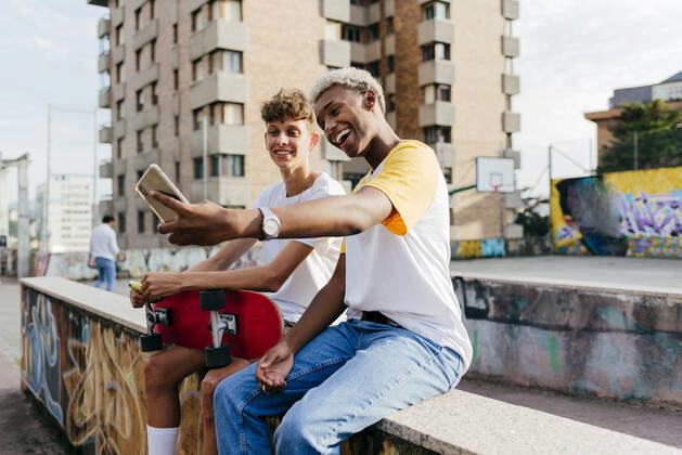 IMAGO Creative, Jahreszeit Sommer, Sommerferien Two handsome teenage boys with skateboard taking selfie on the street, Model released, Property released Copyright: xManuelxRuizxAlbax MR
