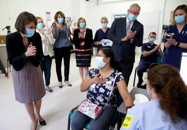 NSW COVID19 VACCINE ROLLOUT, Gayathry Vellangalloor Srinivasan, an Environmental Services Supervisor, is watched by NSW Premier Gladys Berejiklian (left), NSW Chief Medical Health Officer Kerry Chant (fifth right) and NSW Health Minister Brad Hazzard (third right) as she receives the states first Pfizer vaccination at the Royal Prince Alfred Hospital Vaccination Hub in Sydney, Monday, February 22, 2021. Australia will begin its roll out of the Pfizer coronavirus vaccine on Monday, the country s most complicated logistical exercise to date. ( NO ARCHIVING, EDITORIAL USE ONLY, NO USE IN BOOKS WITHOUT CONSENT SYDNEY NSW AUSTRALIA  Copyright: xTobyxZernax 20210222001522236535