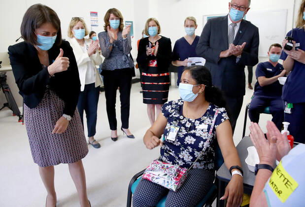 NSW COVID19 VACCINE ROLLOUT, Gayathry Vellangalloor Srinivasan, an Environmental Services Supervisor, is watched by NSW Premier Gladys Berejiklian (left), NSW Chief Medical Health Officer Kerry Chant (second right) and NSW Health Minister Brad Hazzard (right) as she receives the states first Pfizer vaccination at the Royal Prince Alfred Hospital Vaccination Hub in Sydney, Monday, February 22, 2021. Australia will begin its roll out of the Pfizer coronavirus vaccine on Monday, the country s most complicated logistical exercise to date. ( NO ARCHIVING, EDITORIAL USE ONLY, NO USE IN BOOKS WITHOUT CONSENT SYDNEY NSW AUSTRALIA  Copyright: xTobyxZernax 20210222001522248548