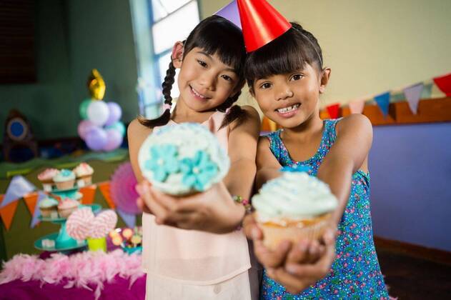 IMAGO Creative: Gesellschaft, Schule, Schulanfang Kids having cupcake during birthday party at home Portrait of kids having cupcake during birthday party at home, model released, , property released, Cape Town, South Africa, 2017-04-24T23:00:00.000Z, 1049243.jpg, home, house, household, homey, apartment, domicile, abode, living room, birthday, birthday party, party, anniversary, event, casual clothing, party hat, standing, smiling, happy, cheerful, holding, cupcake, sweet food, dessert, tasty, delicious, adorable, cute, childhood, innocence, friend, friendship, together, bonding, celebration, leisure, lifestyle Child, Girl, Female, Chinese, Mixed-Race, 8-9 Years, Girls, Chinese Ethnicity, Mixed-Race Person Indoors,Portrait,Looking at camera,Half length