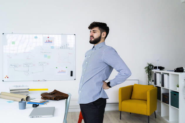 Tired businessman stretching in office model released Symbolfoto property released GIOF10574