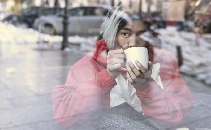 Asian man drinking coffee seen through glass in cafe during winter model released Symbolfoto JCCMF01139