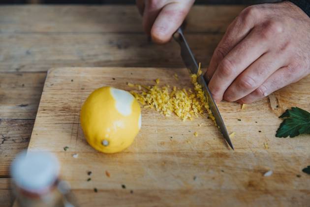 Close-up of chef cutting lemon peel on cutting board in kitchen model released Symbolfoto property released MFF06962