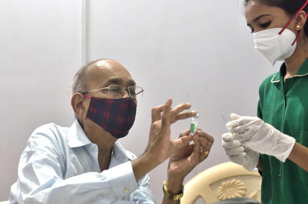 MUMBAI, INDIA - MARCH 1: A senior citizen inspects a Covishield vial while getting their first dose of a Covid-19 vaccination, at BKC on March 1, 2021 in Mumbai, India. India?s Covid-19 vaccination drive was extended today to include the elderly and those with co-morbidities. (Photo by Satish Bate Hindustan Times) Covid Vaccination Phase 2 Starts In India