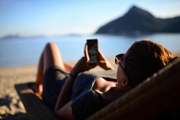 IMAGO Creative, Jahreszeit Sommer, Sommerferien Young woman uses the smartphone on the beach Palma, IB, Spain CR_RBIG210305-670348-01 ,model released, Symbolfoto