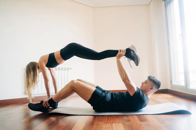 IMAGO Kreativ: Bildung, Sporterziehung Full body side view of determined man and woman wearing sportive clothes performing difficult yoga position while practicing at home Copyright: xJakexJakabx Model Released
