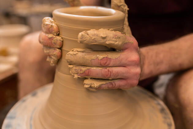 Crop unrecognizable sculptor with equipment giving shape while sculpting with brown clay on throwing wheel, Model released Copyright: xMiguelxVallsx MR