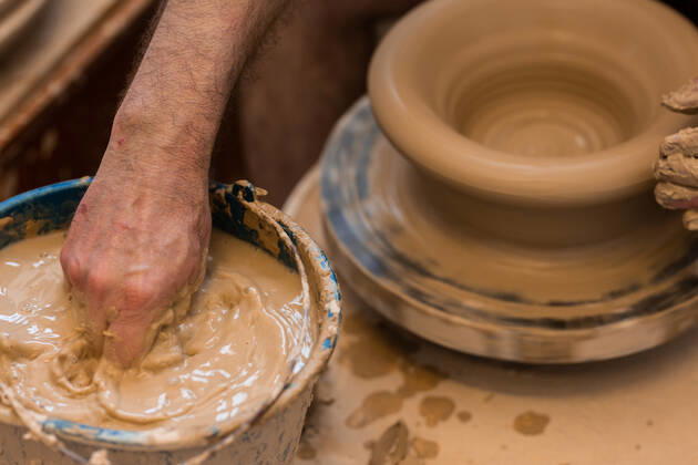 Crop unrecognizable sculptor with equipment giving shape while sculpting with brown clay on throwing wheel, Model released Copyright: xMiguelxVallsx MR