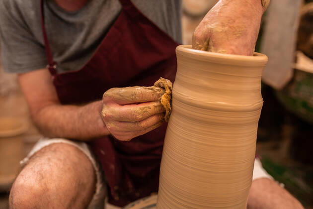 Crop unrecognizable sculptor with equipment giving shape while sculpting with brown clay on throwing wheel, Model released Copyright: xMiguelxVallsx MR