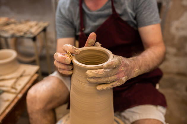 Crop unrecognizable sculptor with equipment giving shape while sculpting with brown clay on throwing wheel, Model released Copyright: xMiguelxVallsx MR