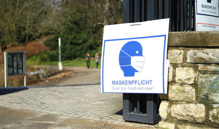 At the entrance of a green area in Hamburgs city centre there are signs indicating that masks are compulsory in this park on weekends and public holidays from 10 a.m. to 6 p.m. City centre Hamburg