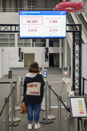 DEUTSCHLAND, Hamburg, Corona Pandemie, Impfzentrum der KVH und Sozialbehörde Hamburg in den Messehallen, groesstes Impfzentrum Deutschlands fuer bis zu 7000 Menschen taeglich, Impfung von alten Menschen und jungen Menschen in systemrelevanten Berufen, Mitarbeiter Eingang mit digitaler Fiebermessung Hamburg Germany