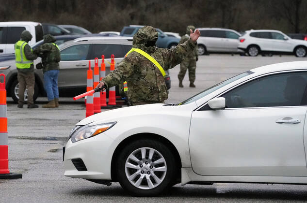 Missouri National Guardsmen direct traffic as cars line up for vaccination shots at the Family Arena during a mass vaccination drive-in event in St. Charles, Missouri on Thursday, March 18, 2021. The event attracted 4,000 people, some waiting over four hours in their cars for their first shot to protect them from the coronavirus.  SLP2021031813 BILLxGREENBLATT