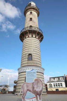 Blick am Donnerstag (18.03.2021) in Warnemünde auf den alten Leuchtturm mit dem Schriftzug Vorsicht Löwe im Mittelpunkt. Gegenwärtig sind in dem Ostseebad nur wenige Ausflügler zwischen dem Teepott und dem Hotel Neptun unterwegs. Dazu wirbt ein Aufsteller mit der Aufschrift Vorsicht Löwe für die Nutzung der Luca – App. Mit ihrer Hilfe kann das Gesundheitsamt die örtlichen Kontakte nachverfolgen. Dazu ist sie ein wichtiges Hilfsmittel zur Öffnung des Tourismus im Nordosten. Denn dieser steckt seit der Ausbreitung des Coronavirus nach wie vor in einer tiefen Krise. Dahingehend ist u.a. bisher völlig unklar, ob die Tourismusbetriebe wieder zu Ostern öffnen können. Eine Entscheidung dazu könnte jedoch am Montag (22.03.2021) beim Bund-Länder-Gip
