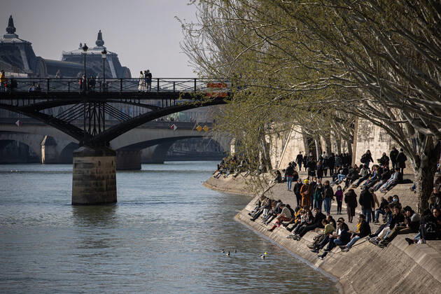 (210320) -- PARIS, March 20, 2021 -- People enjoy sunshine at the bank of Seine in Paris, France, on March 20, 2021. French Prime Minister Jean Castex on Thursday announced new massive measures to curb COVID-19 in the country s 16 worst-hit regions, including Paris. Starting Friday midnight, about 18 million French people in regions such as Paris, Hauts-de-France in the north as well as the Alpes-Maritimes on the Mediterranean should stay at home, Castex announced at a press briefing on the epidemic situation. (Photo by Xinhua) FRANCE-PARIS-COVID-19-PARTIAL LOCKDOWN AurelienxMorissard 