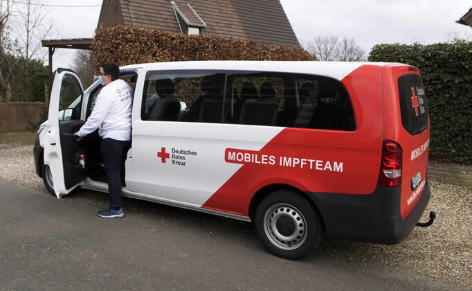 DRK Einsatzfahrzeug Mobiles Impfen Einsatzfahrzeug des DRK Wesel mit der Aufschrift Mobiles Impfteam. Das Fahrzeug wird genutzt zum Transport der Impfdosen zu den Impfzentren oder ambulanten Impforten. Das Fahrzeug steht vor einem Privathaus. Mitarbeiter des DRK Wesel steigt aus dem Einsatzfahrzeug. Moers Deutschland Nordrhein-Westfalen NRW