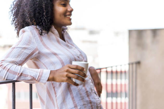 Smiling young female entrepreneur leaning on railing during coffee break at office model released Symbolfoto property released AFVF08426