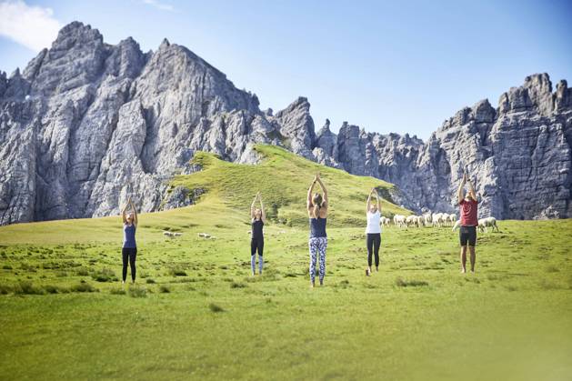 Man and women practicing yoga on meadow against mountain model released Symbolfoto CVF01639