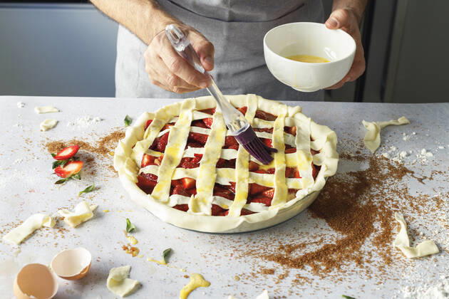 Hands of man applying egg wash to raw strawberry pie model released Symbolfoto property released IFRF00457