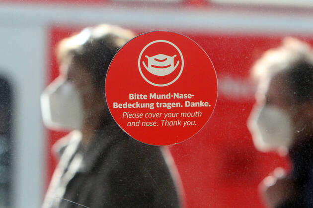 Sticker with pictogram and inscription please wear mouth-nose covering stuck on a window on the platform in the main station of Mannheim, Baden Württemberg, Germany