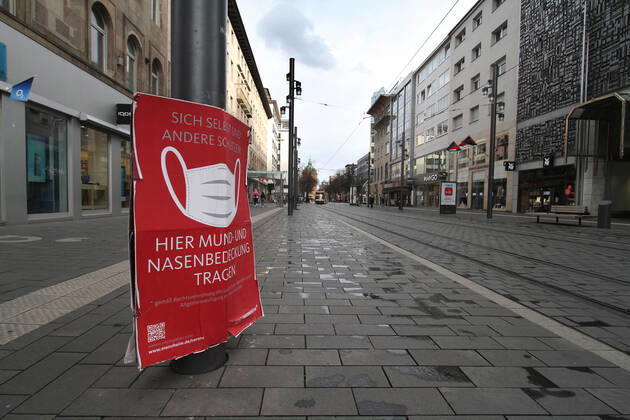 A sign with a pictogram and the inscription Maskenpflicht (mask obligation) hangs in the largely deserted pedestrian zone and shopping street Planken in the city centre of Mannheim, Baden Württemberg, Germany.