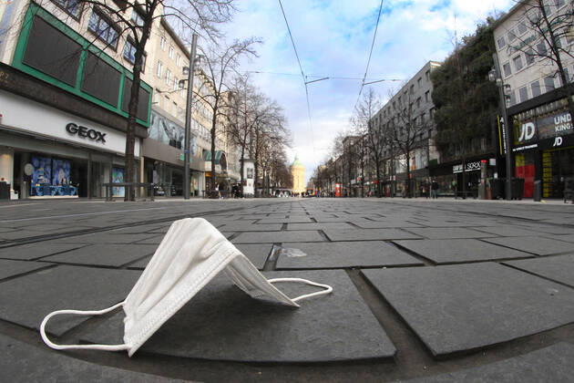 Worn mouth nose covering mask lies on the pavement of the deserted pedestrian zone and shopping street Planken in downtown Mannheim, Baden Württemberg, Germany
