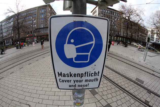 A sign with a pictogram and the inscription Maskenpflicht (mask obligation) hangs in the largely deserted pedestrian zone and shopping street Planken in the city centre of Mannheim, Baden Württemberg, Germany.