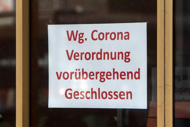 Sign with inscription temporarily closed due to Corona regulation hangs on the entrance door of a closed shop in downtown Mannheim, Baden Württemberg, Germany