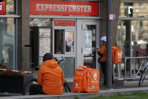 Bicycle courier from the internet portal Lieferando waits in front of a Burger King branch for food delivery in downtown Mannheim, Baden Württemberg, Germany