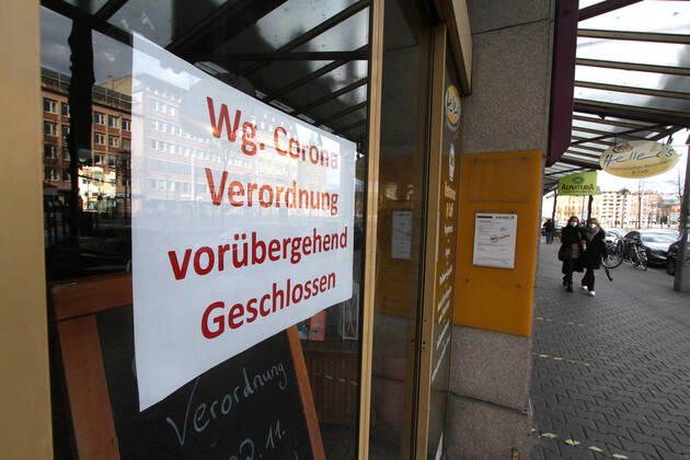 Sign with inscription temporarily closed due to Corona regulation hangs on the entrance door of a closed shop in downtown Mannheim, Baden Württemberg, Germany