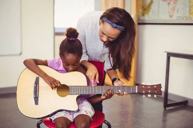 IMAGO Creative: Bildung, Musikerziehung Teacher assisting a girl to play a guitar in classroom Teacher assisting a girl to play a guitar in classroom at school, model released, , property released, Cape Town, South Africa, 06.03.2016, 748648.jpg, classroom, class, student, primary, school, schoolgirl, schoolchild, teacher, casual clothing, playing, guitar, siting, chair, helping, assisting, showing, pointing, music, entertainment, music instrument, string instrument, learn, learning, hobbies, development, education, knowledge, adorable, elementary, elementary school, back to school, academic, lifestyle, leisure, childhood, guidance 20s, Young Adult, Woman, Female, Mixed-Race, Child, Girl, Black, 20-24 Years, Young Women, Mixed-Race Person, 10-11 Years, Girls, African Ethnicity I