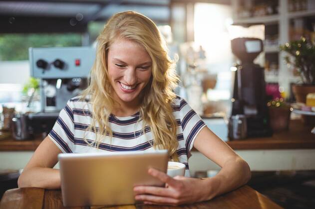 Woman sitting in a cafe using digital tablet Smiling woman sitting in a cafe using digital tablet, model released, , property released, Cape Town, South Africa, 30.05.2016, 797481.jpg, table, cafe, coffee shop, cafeteria, restaurant, hotel, casual clothing, sitting, holding, smiling, cheerful, web, internet, touching, reading, scrolling, digital tablet, tablet computer, tablet pc, touchscreen, wireless technology, communication, connection, happy, lifestyle, leisure, pretty, attractive Indoors,Day